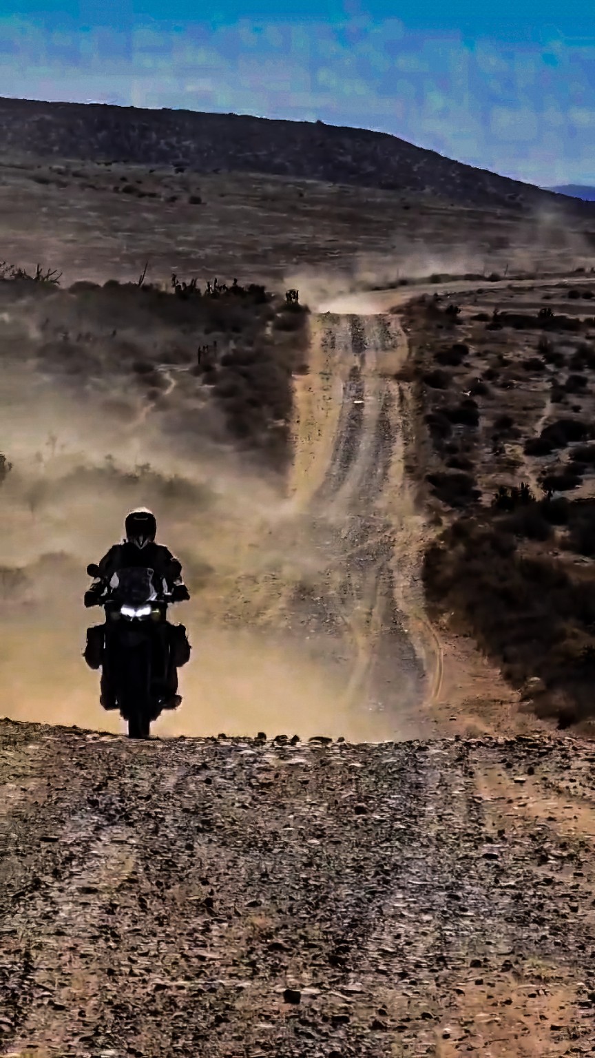 Piloto recorriendo una subida de terracería entre polvo y desierto