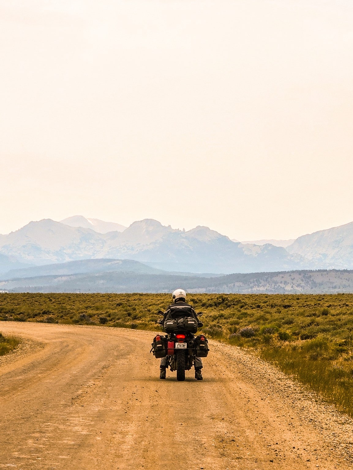 Motociclista en una terracería con montañas al fondo