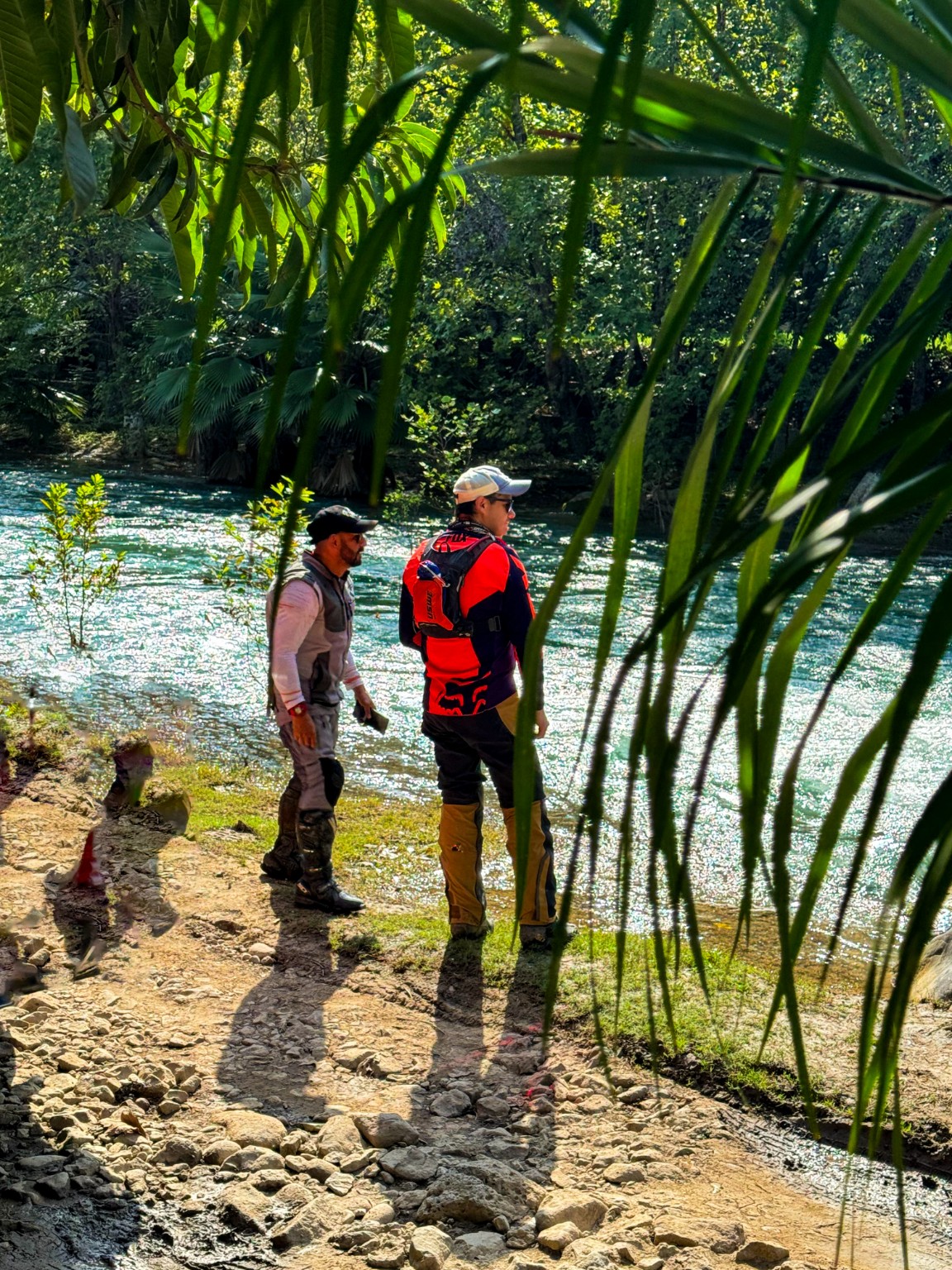 Viajeros junto a un río de agua azul entre vegetación