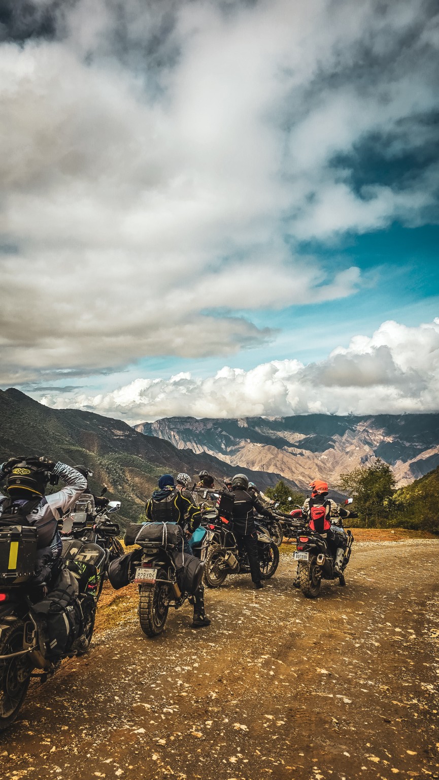 Grupo de motocicletas y pilotos en un camino con vista a las montañas